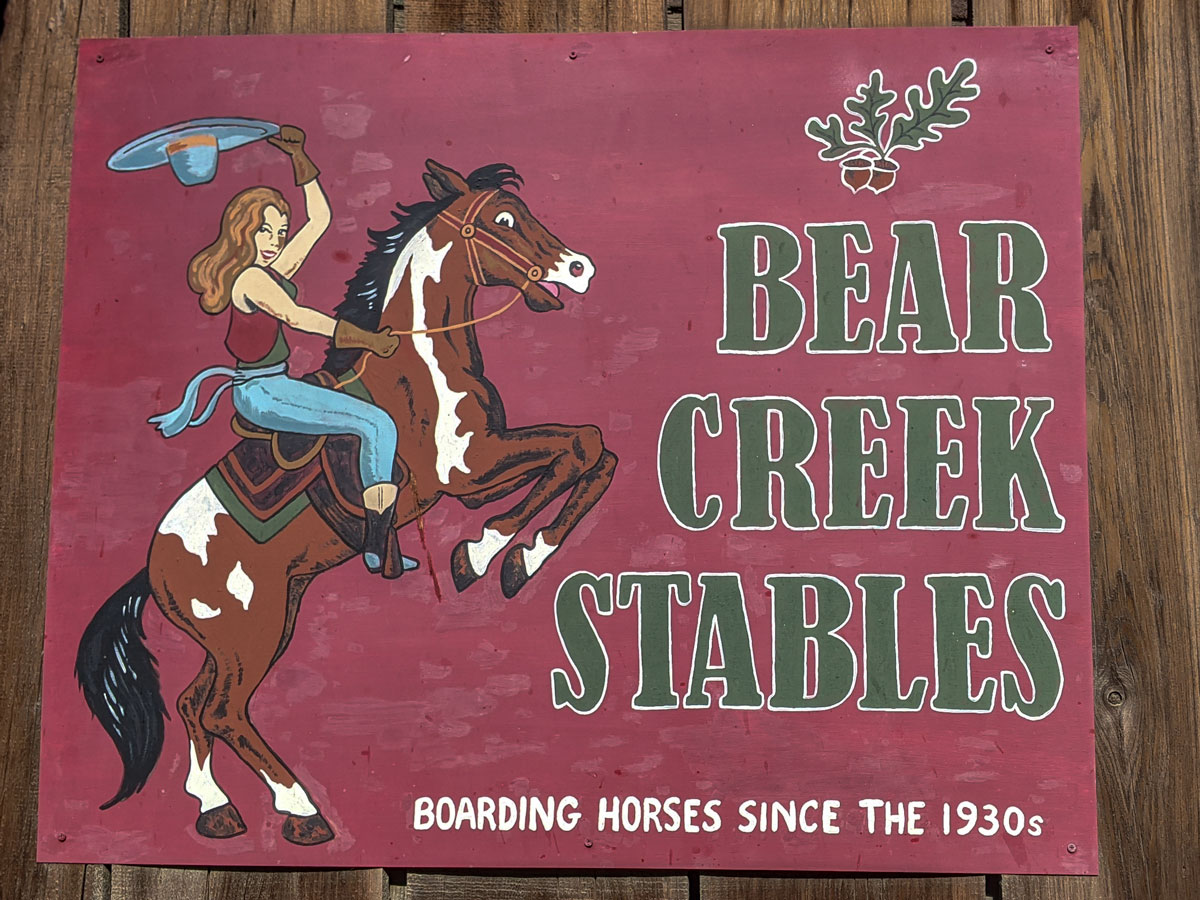 Sign with a woman on a horse rearing against a deep red background.